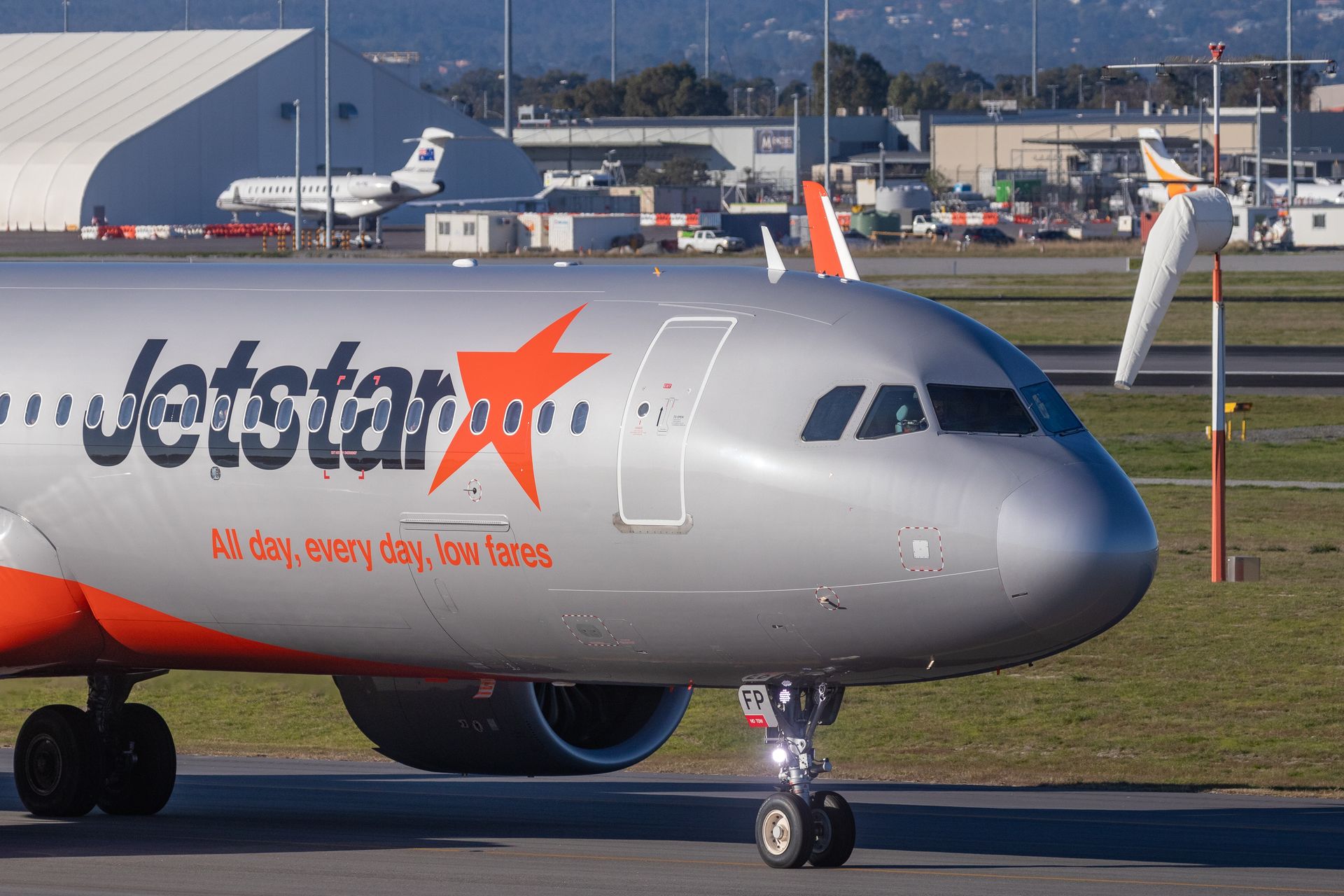 Jetstar aircraft taxiing at an Australian aerodrome with CASA-compliant Windsock visible